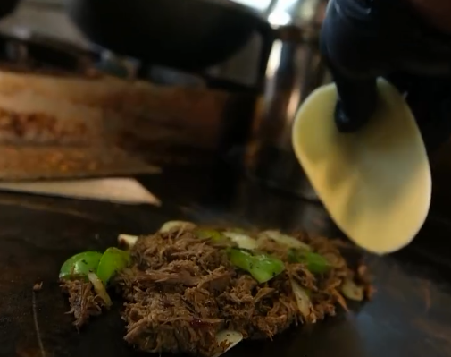 A Rollup team member adding sauce to a freshly prepared roll